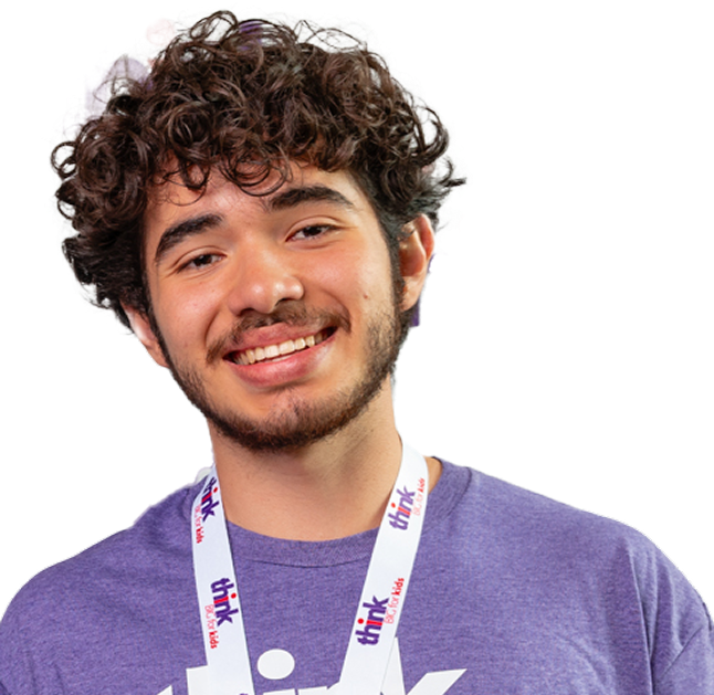 Smiling person with curly hair wearing a purple shirt and lanyard